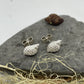 Silver whelk shell stud earrings lying on a stone 