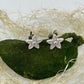 Tiny handmade fine silver flower stud earrings set on a natural green piece of moss