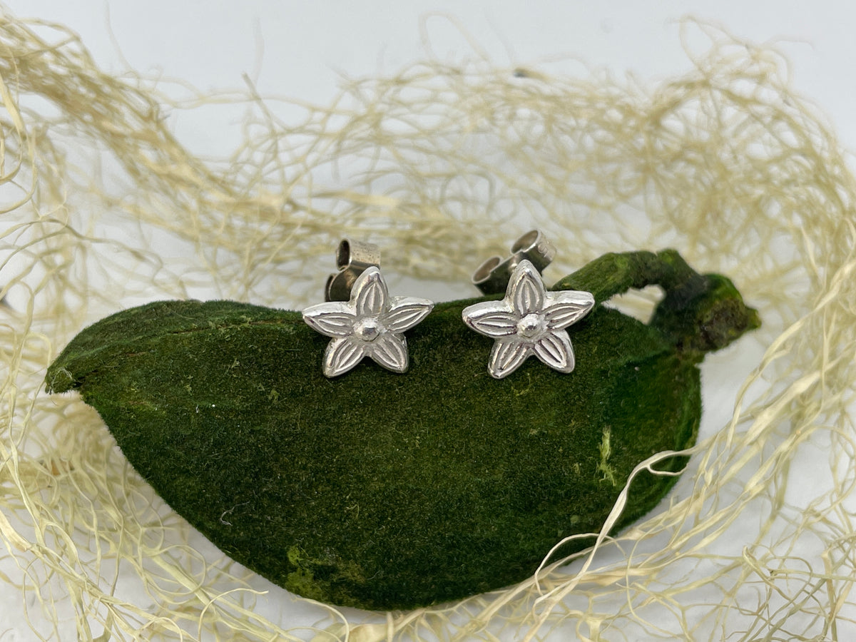 Tiny handmade fine silver flower stud earrings set on a natural green piece of moss