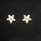 Close up of tiny silver flower stud earrings on a black background